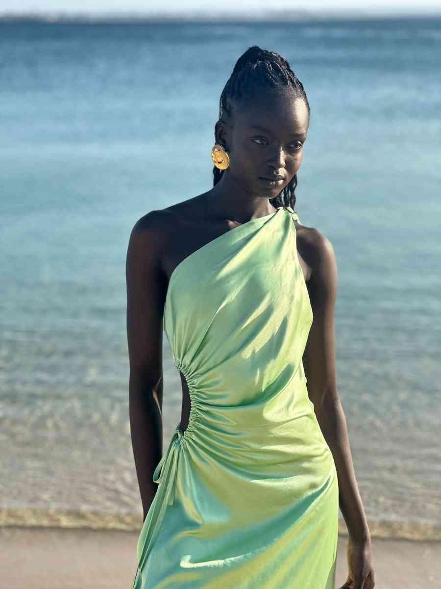 Light green halter maxi dress with circular waist cutout and gathered skirt detail.