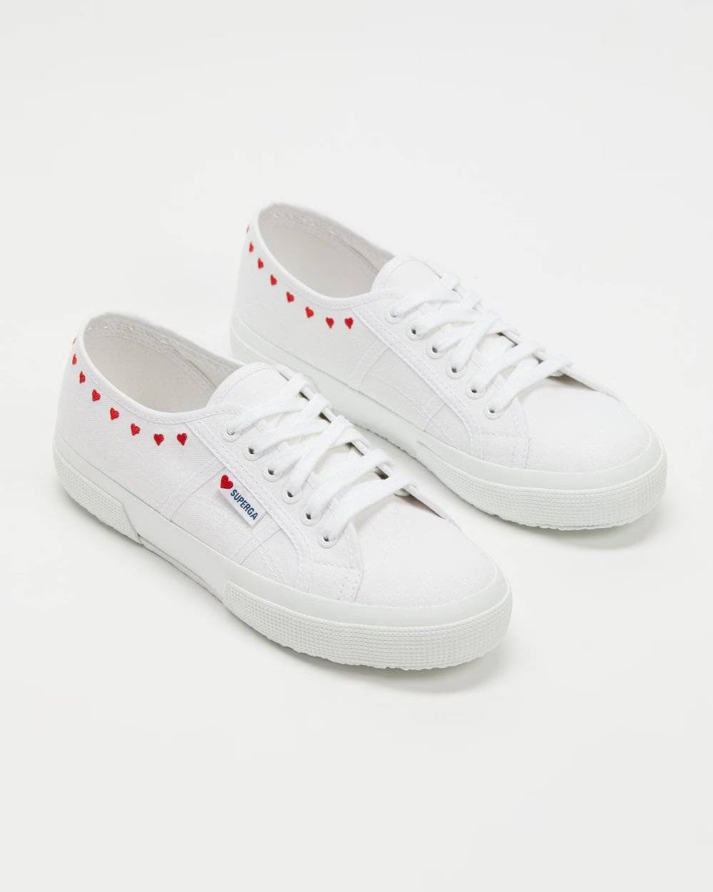 Pair of white low-top sneakers with red heart embroidered trim and rubber platform sole