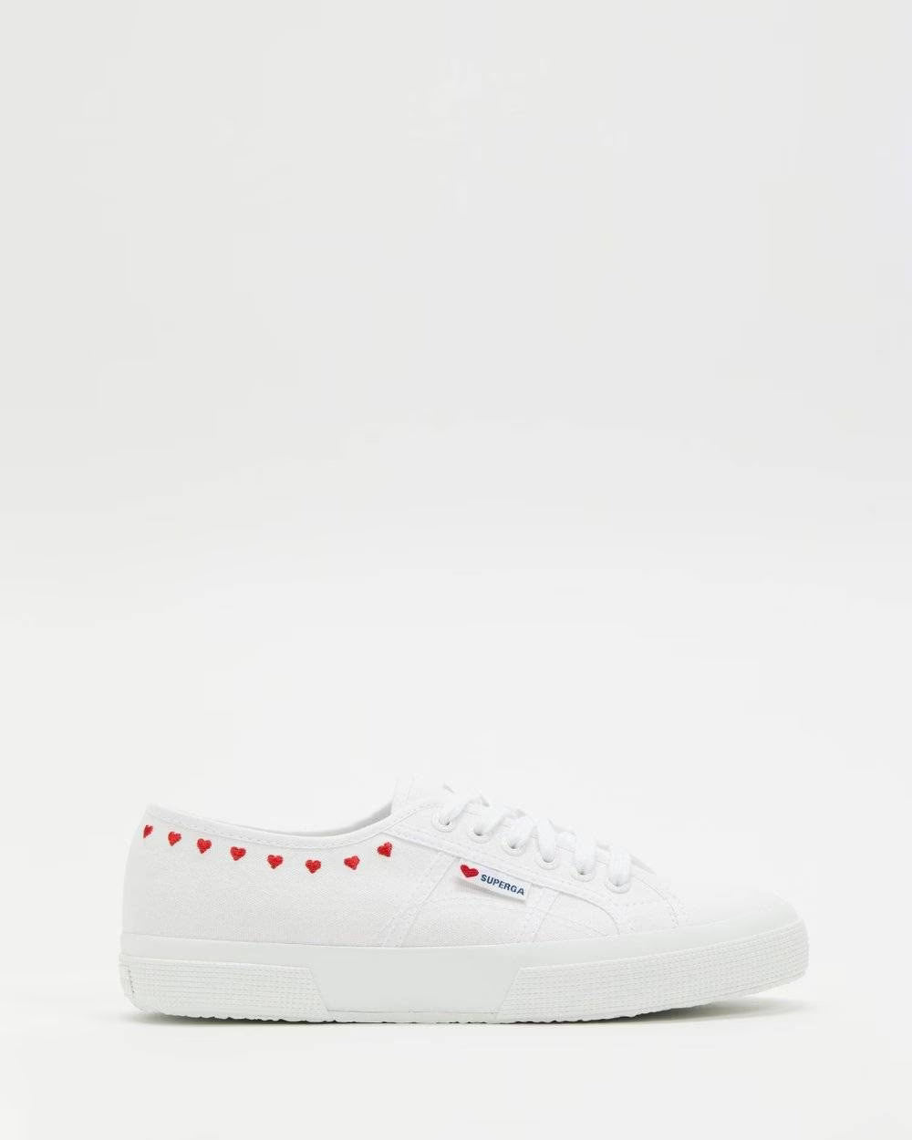 White lace-up sneakers with red heart embroidery along the front collar