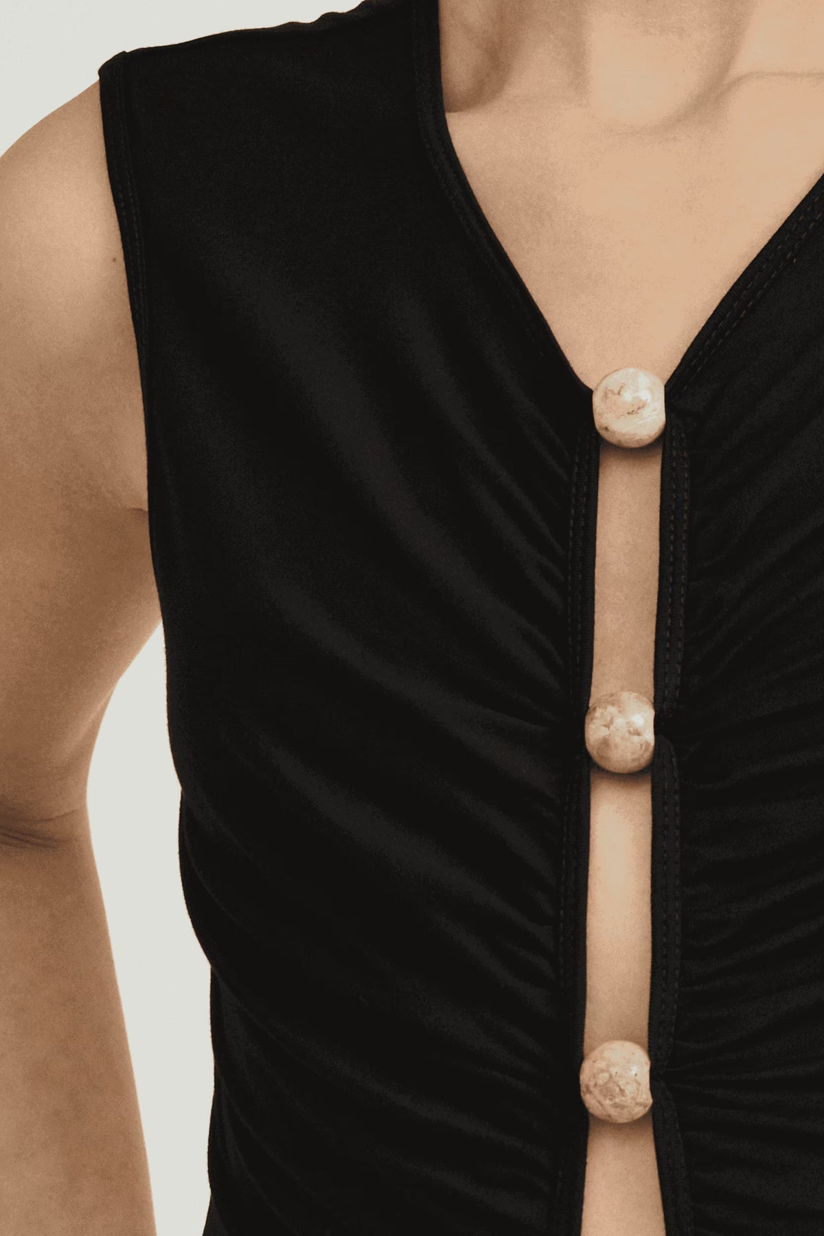 Black sleeveless tank dress close-up: V-neck and button-front placket with light buttons