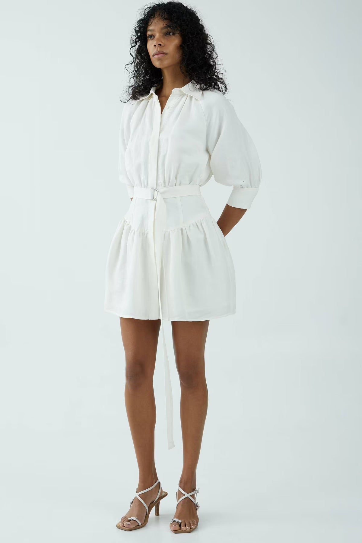 Off-white shirt dress, belted waist and puff sleeves, above-knee length, side view