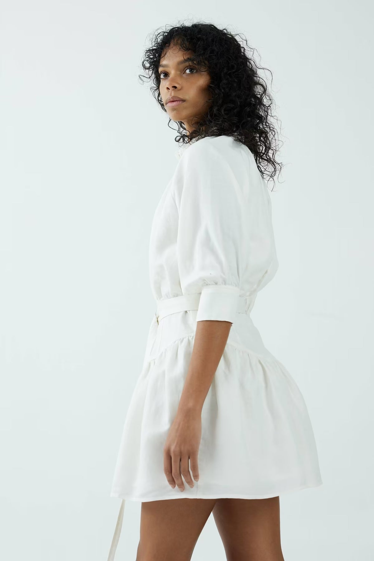 Off-white shirt dress with puff sleeves and tie belt, three-quarter side view