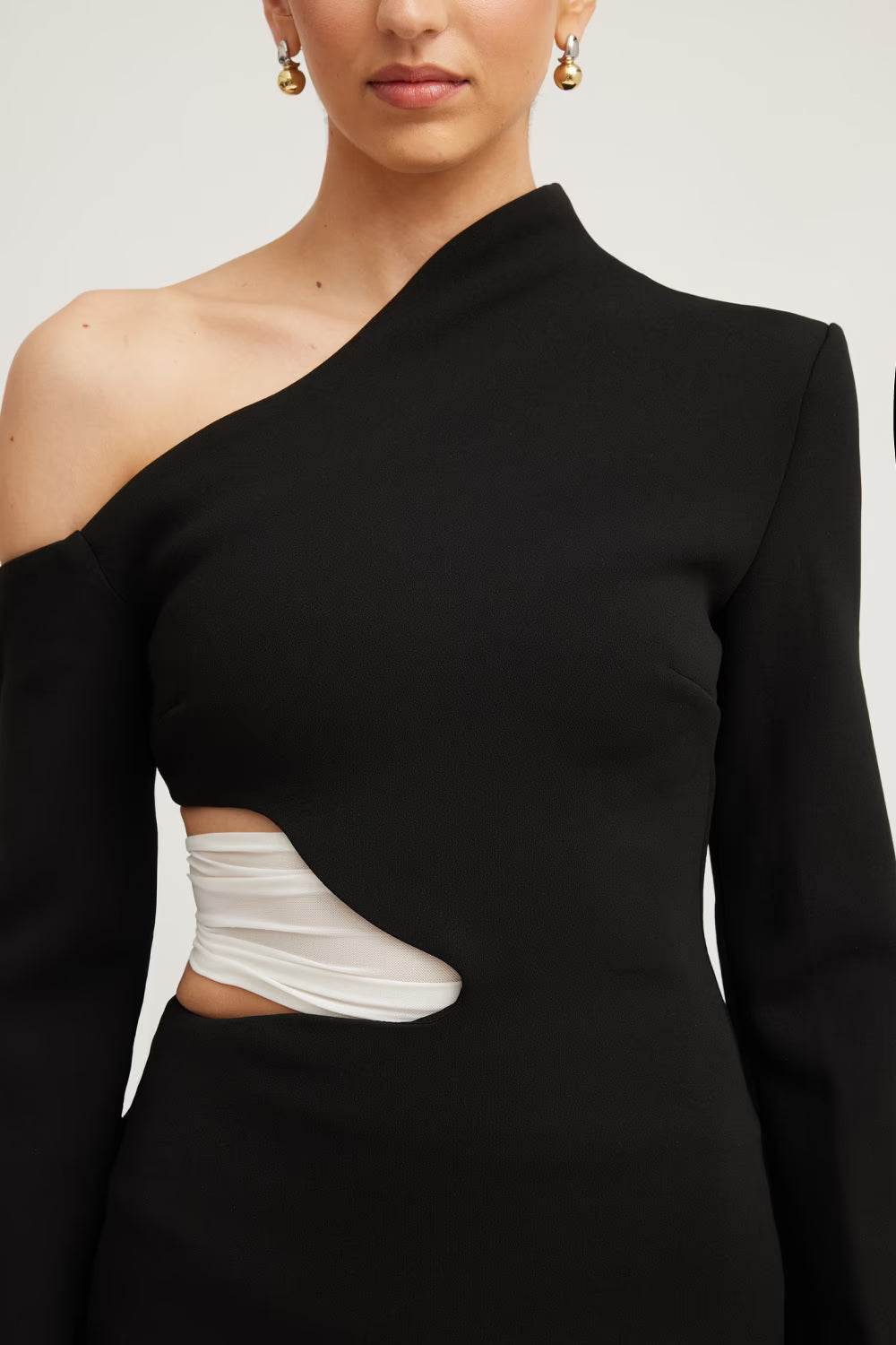 Black one-shoulder mini dress with white curved side cutout, close-up