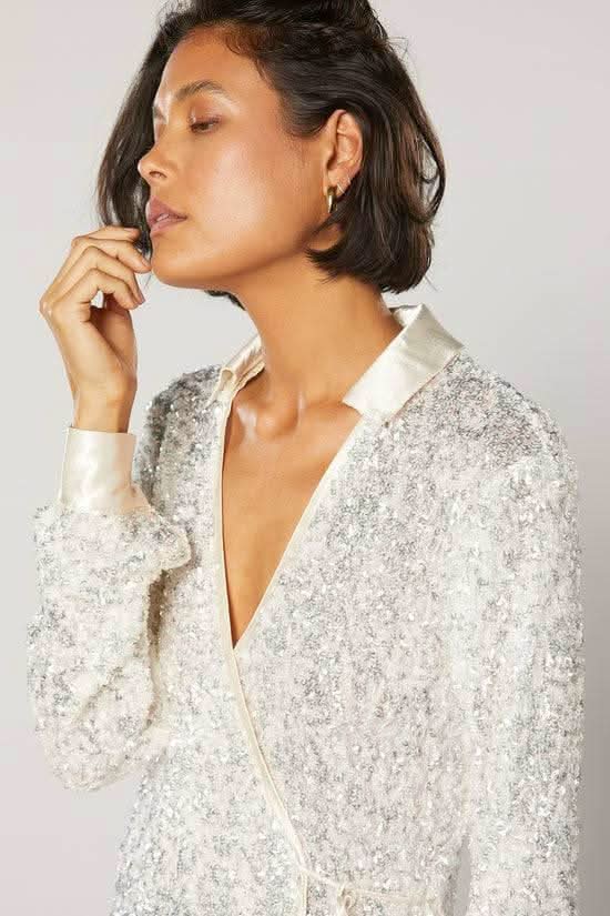 White speckled wrap shirt with deep V neckline and long sleeves, front tie detail.