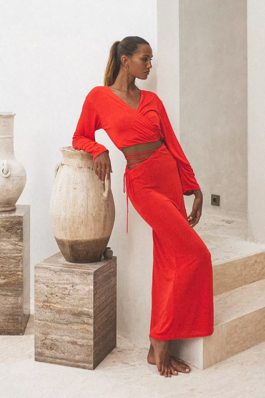 Red long-sleeve wrap top with V-neck and tied waist, shown with matching skirt