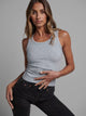 Woman wearing a gray tank top and black pants against a gray background