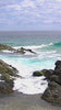 a man standing on top of a rock next to the ocean