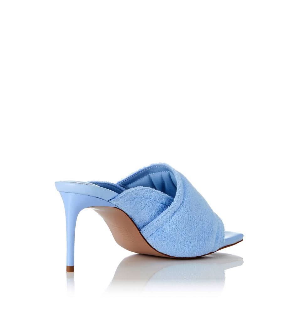 Pale blue terry slide heeled mule with open toe and wide cuff strap over foot
