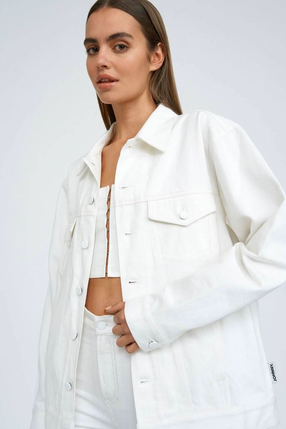 White denim jacket with chest flap pockets and oversized sleeves, close-up