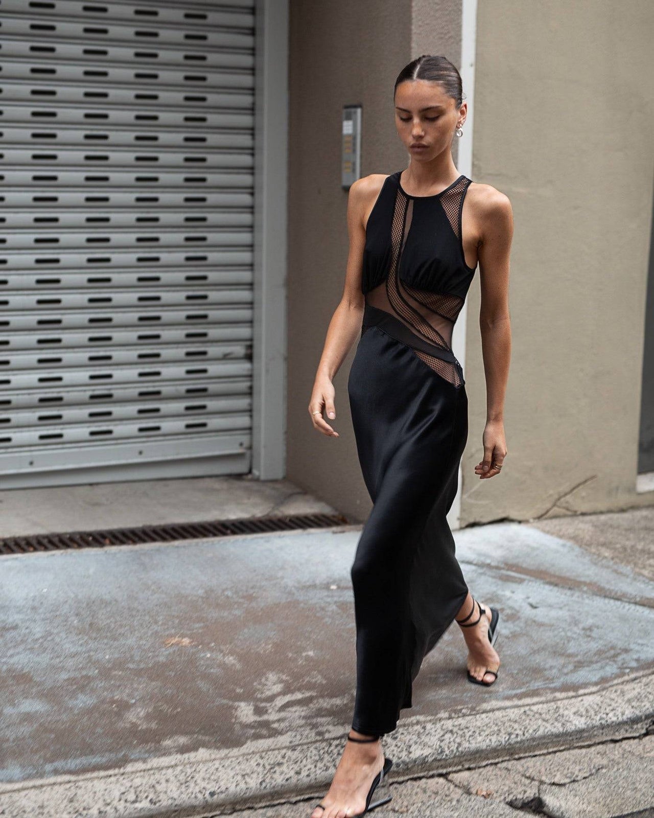 a woman in a black Third Form Crystal Clear Maxi Tank Dress is walking down the street