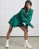 a woman in a green Bare by Charlie Holiday The Long Sleeve Shirt and white tennis shoes