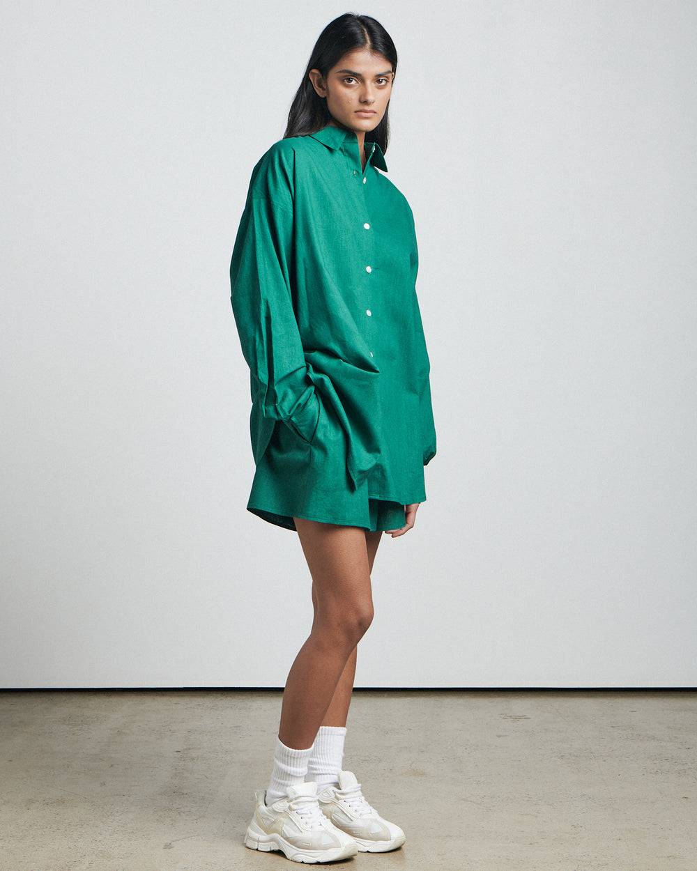 a woman in a green Bare by Charlie Holiday The Long Sleeve Shirt and white tennis shoes